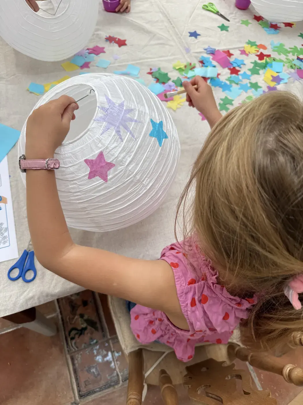 A child sticking paper shapes onto a paper lantern