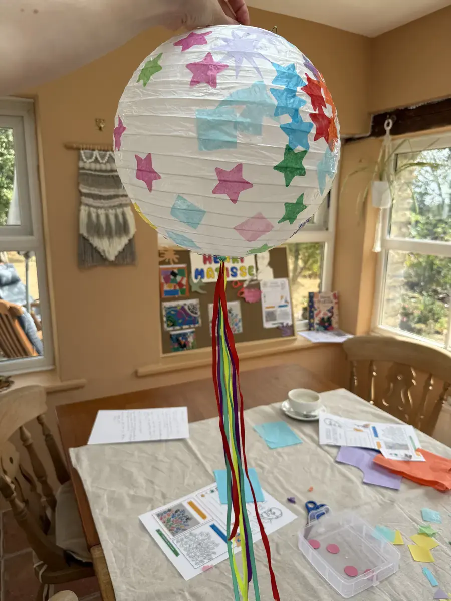A decorated paper lantern hanging with coloured ribbons
