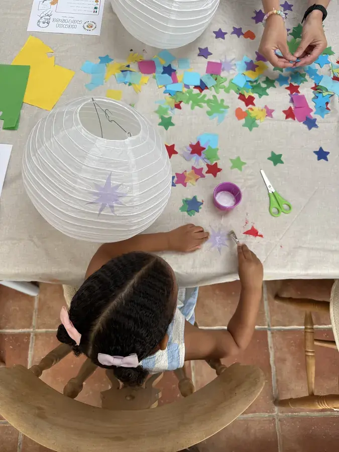A child sticking paper stars onto a paper lantern, seen from above