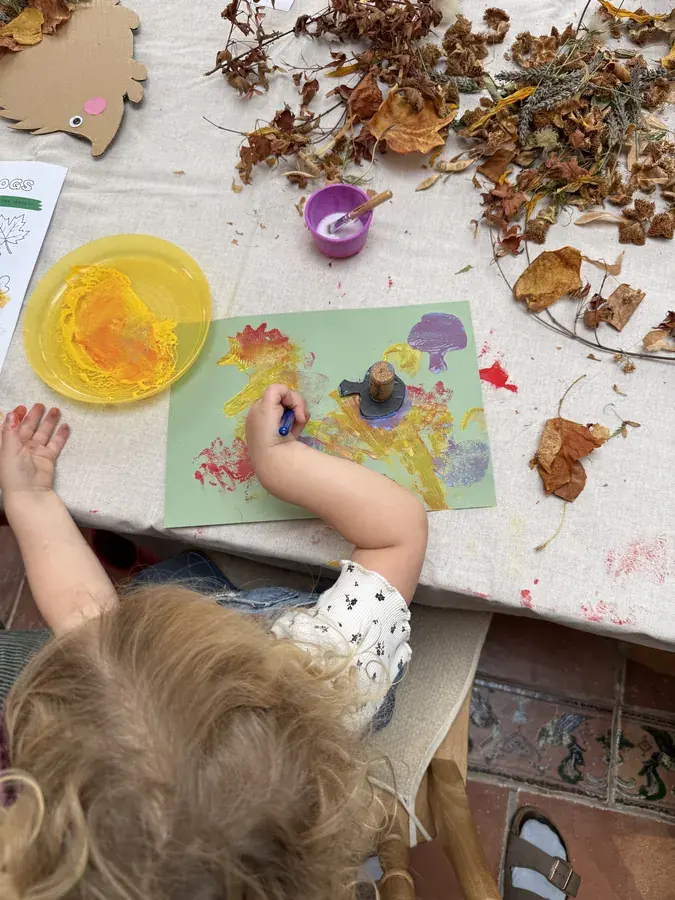 A child printing with paint onto green paper